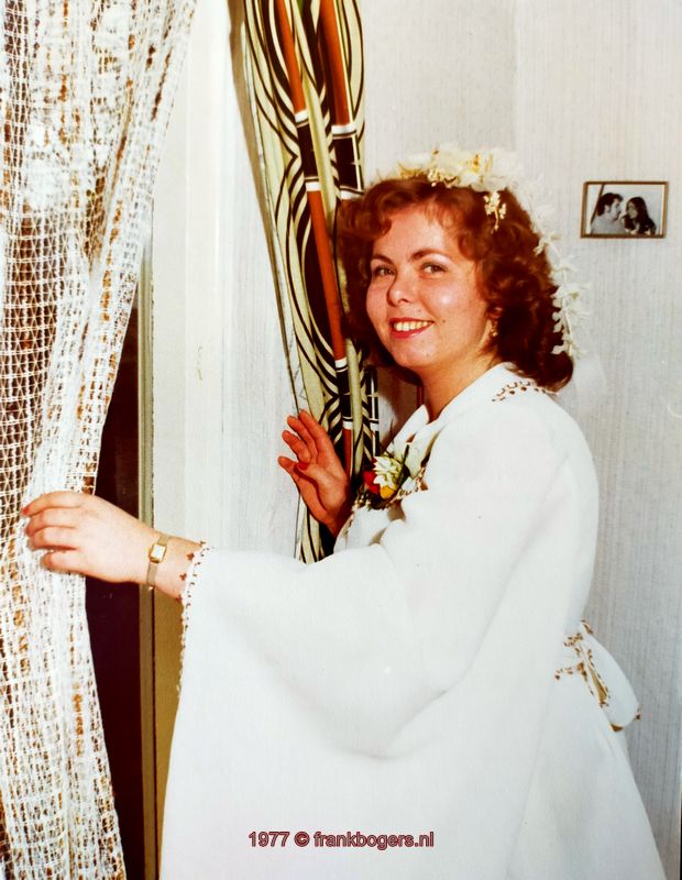 Opgemaakte bruid kijkt door het raam, waar de bruidegom blijft